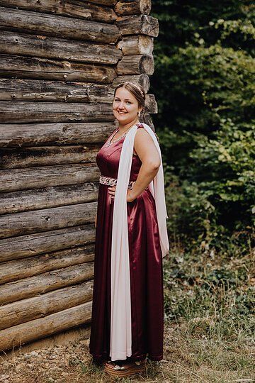 Limeskönigin 2025, Bernadette Marzodko Person in langem Kleid vor Holzturm