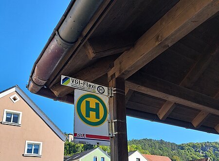 Bushaltestelle mit Vordach, im Hintergrund Fahrzeuge
