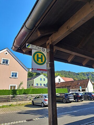Bushaltestelle mit Vordach, im Hintergrund Fahrzeuge