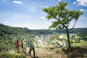 Familie mit Rangerin auf der sommerlichen Arnsberger Leite mit Talblick im Hinergrund. 