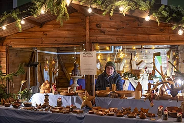 Holzkünstlerin mit Holzobjekten in Marktbude.