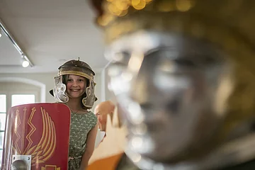 Kind probiert im RömerMuseum Held und Schild an.