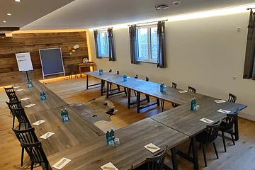 Die holzigen Tische sind in U-Form aufgestellt, mit Blick zur Tafel.