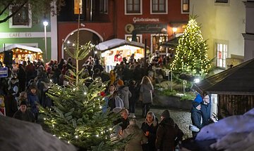 Weihnachtsbuden und leuchtende Christbäume am Kipfenberger Marktplatz. WEihnachtsmarktbesucher.
