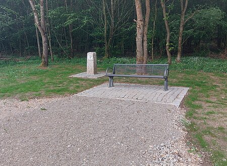 Grenzstein in Biberg mit Sitzgelegenheit Sitzbank und Grenzstein vor bewaldeter Fläche