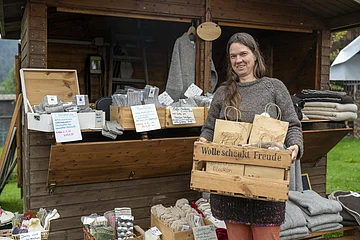 Handwerkerin vor ihrer Verkaufsbude mit Produktkiste in der Hand