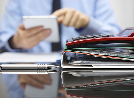 files and folders and businessman in background with tablet pc in hands